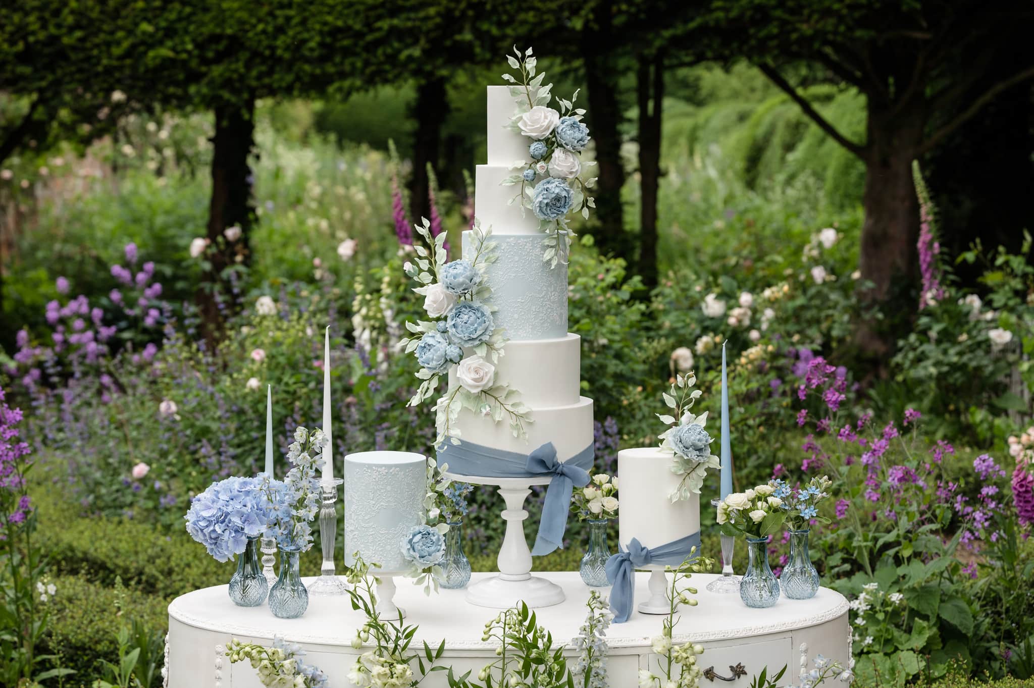 Pale blue and white wedding cakes on a white dressing table