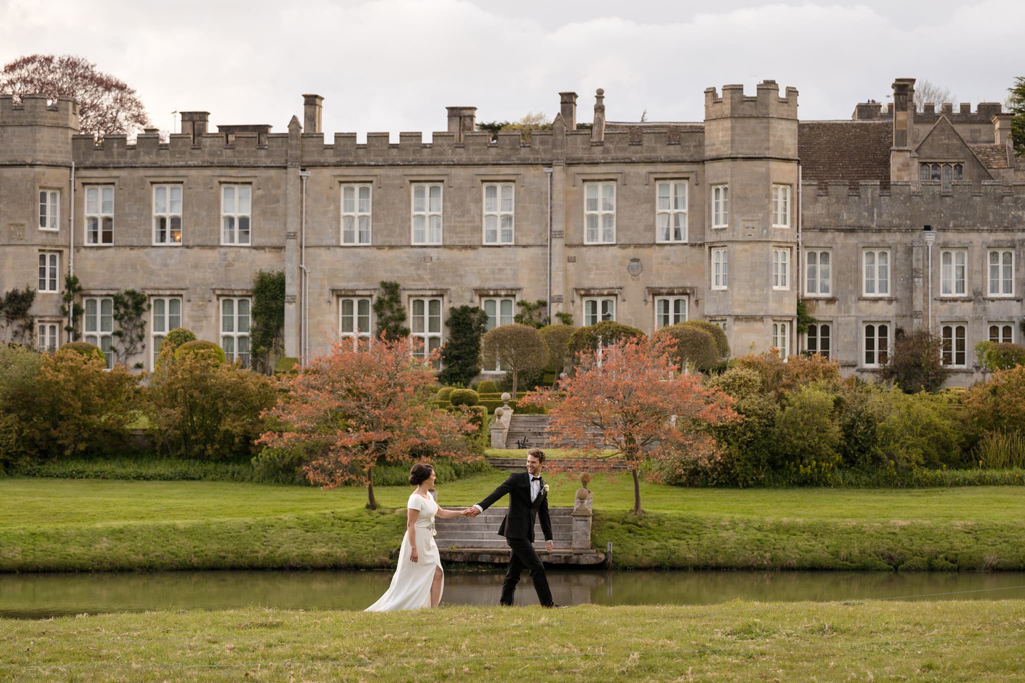 Bride and groom walking in front of Deene Park house