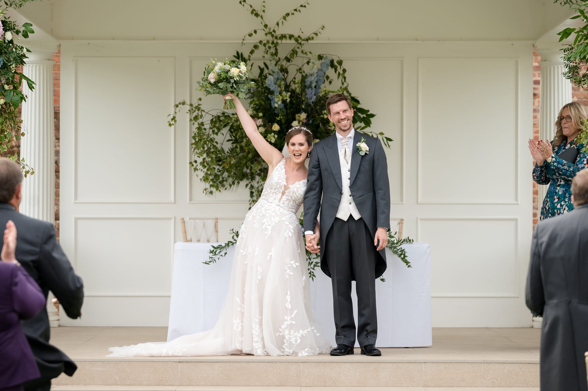 Bride holding her bouquet in the air as the couple prepare to walk back down the aisle