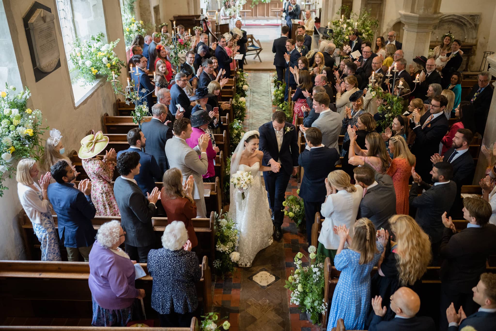 A view of the bride and groom walking down the aisle from the organist's balcony at Grantchester church