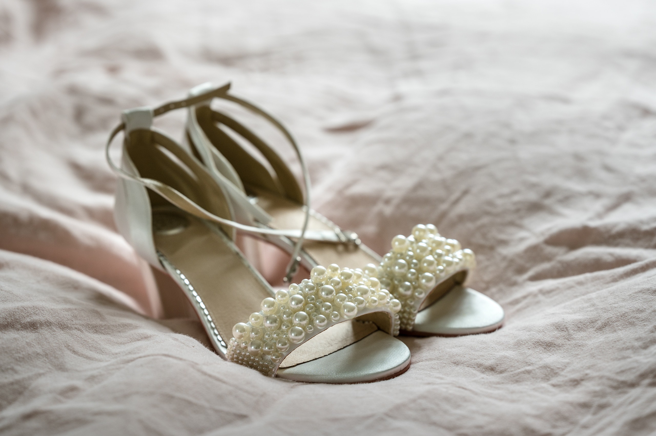 A bride's wedding shoes on pale pink linen