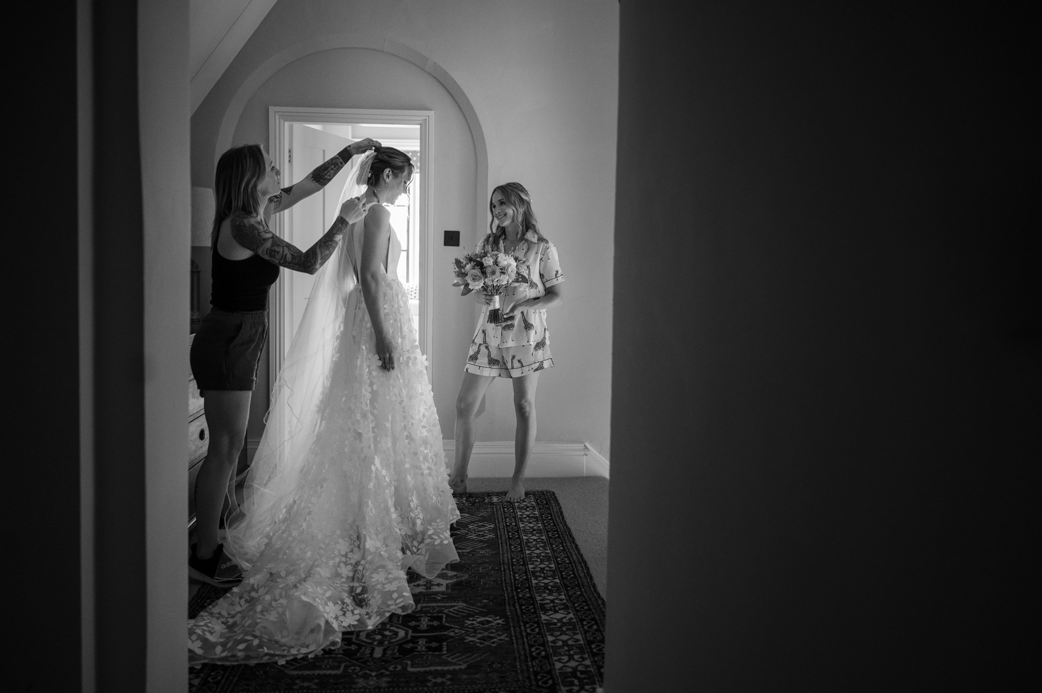 The hair styist fitting the bride's veil as a bridesmaid watches on