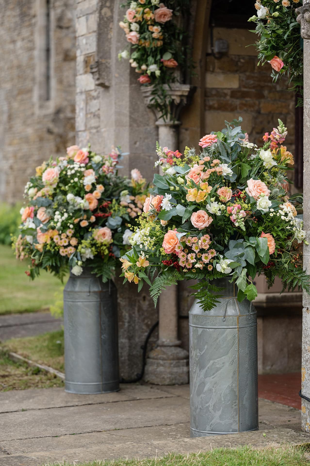 Two milk churns filled with fresh flowers at Wing church in Rutland