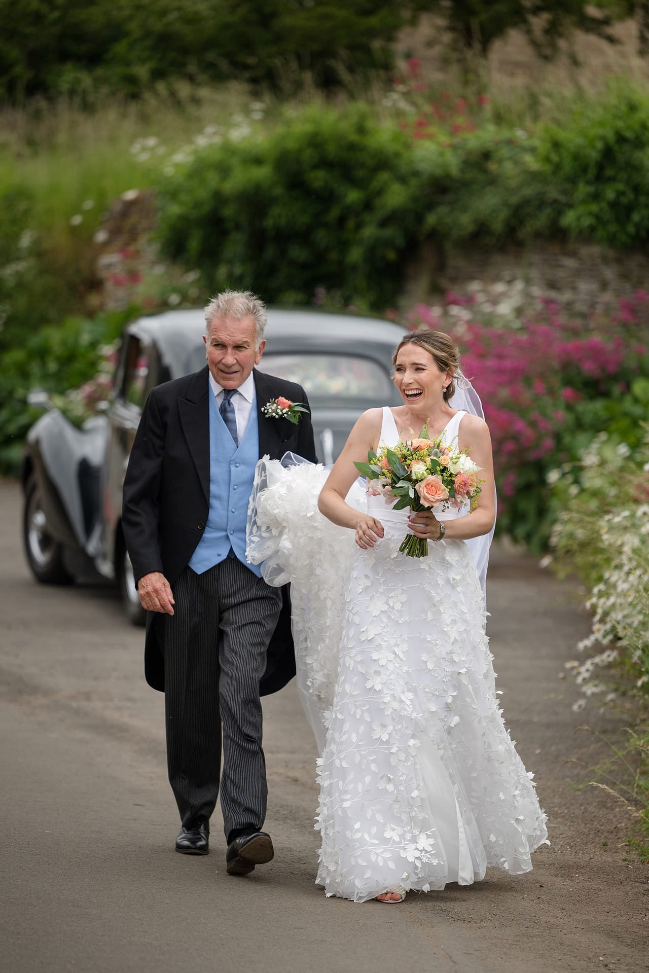 The bride and her dad walking away from the wedding car outside Wing church in Rutland