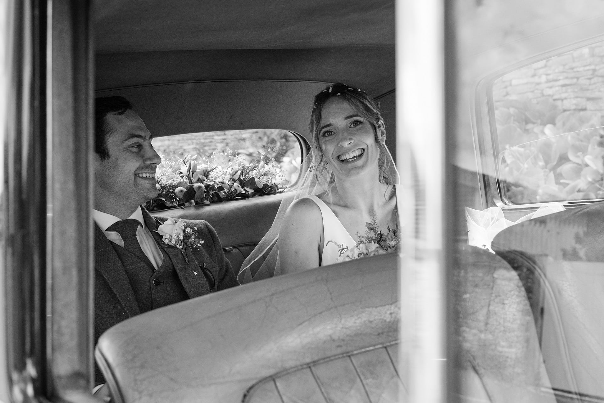 Bride and groom in the back of their vintage wedding car