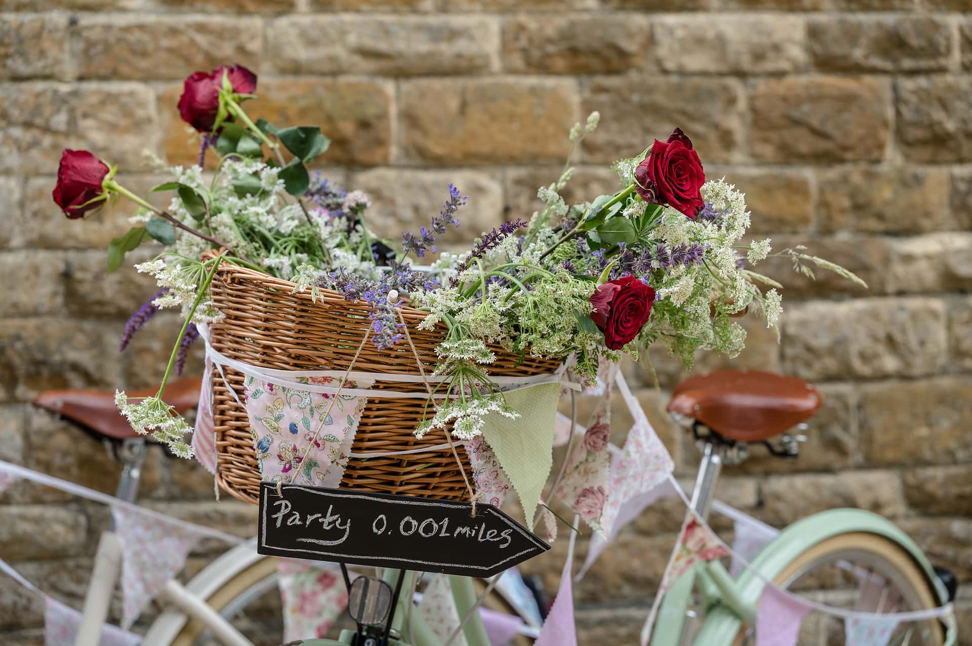 Bicycle baskets filled with fresh flowers and a 'party 0.001 miles' sign