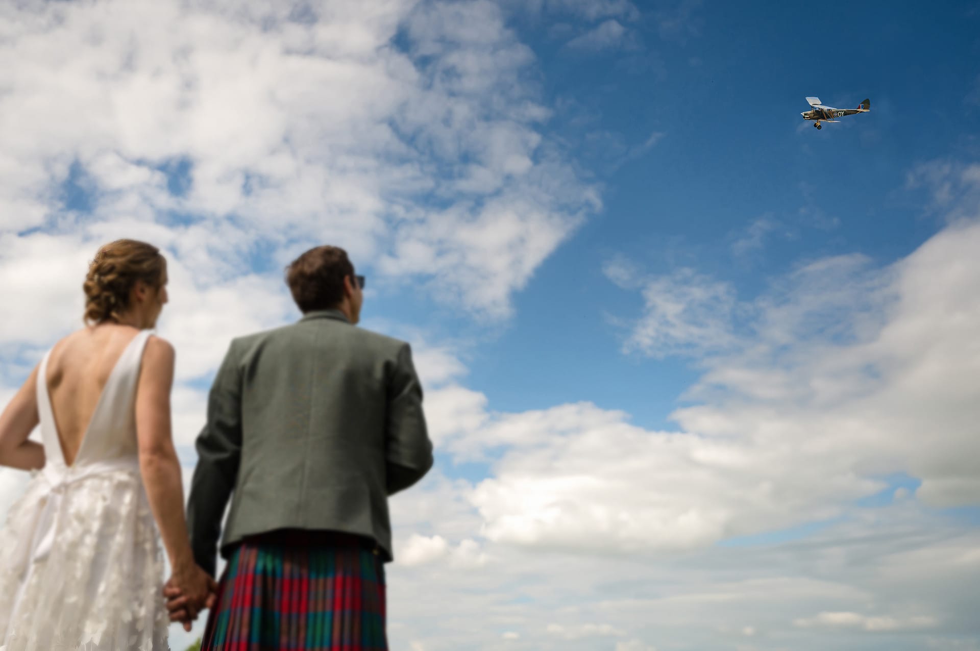 Bride and groom looking on as a vintage tiger moth plane flies past