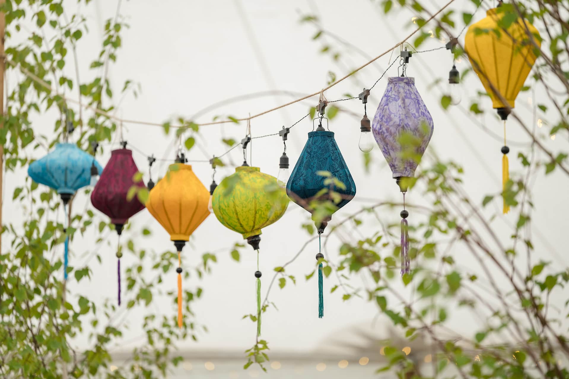 Brightly coloured lanterns and festoon lights strung from marquee poles