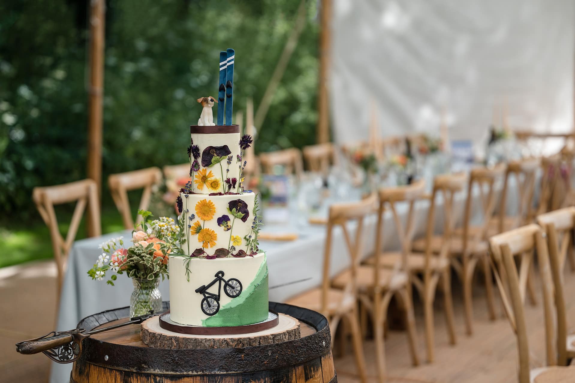 A wedding cake showing the bride and groom's shared interests of biking, skiing, and their Jack Russell dog