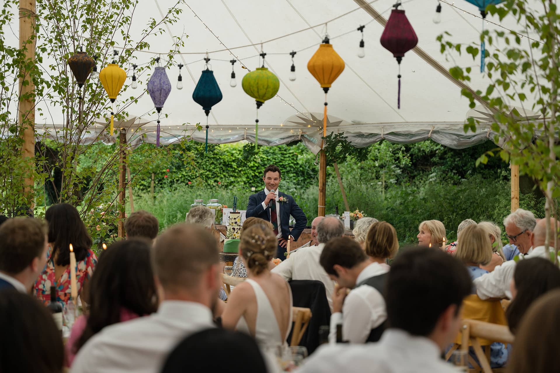 The best man making a speech to a marquee full of people