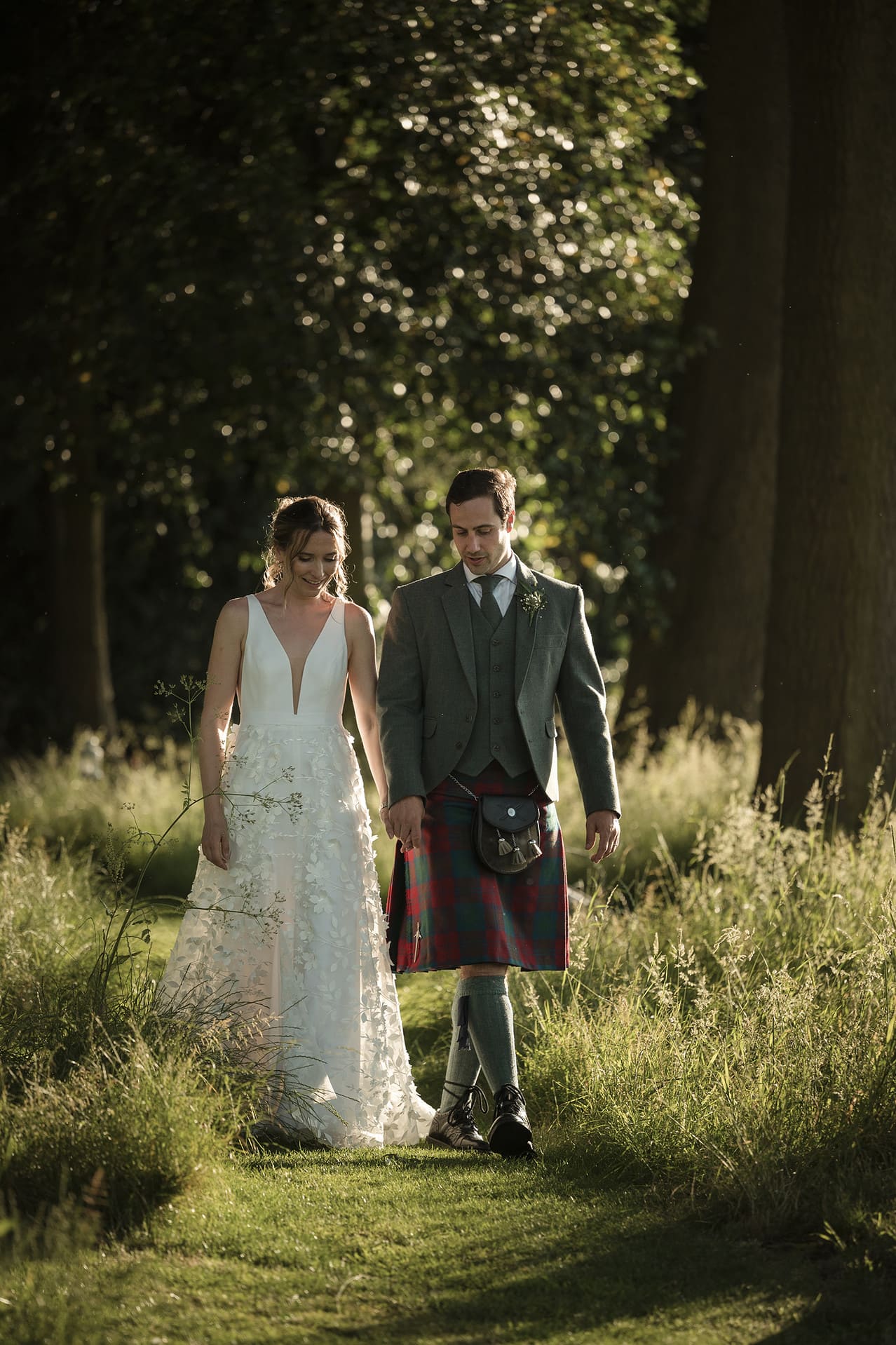 Bride and groom walking through some woodland during golden hour