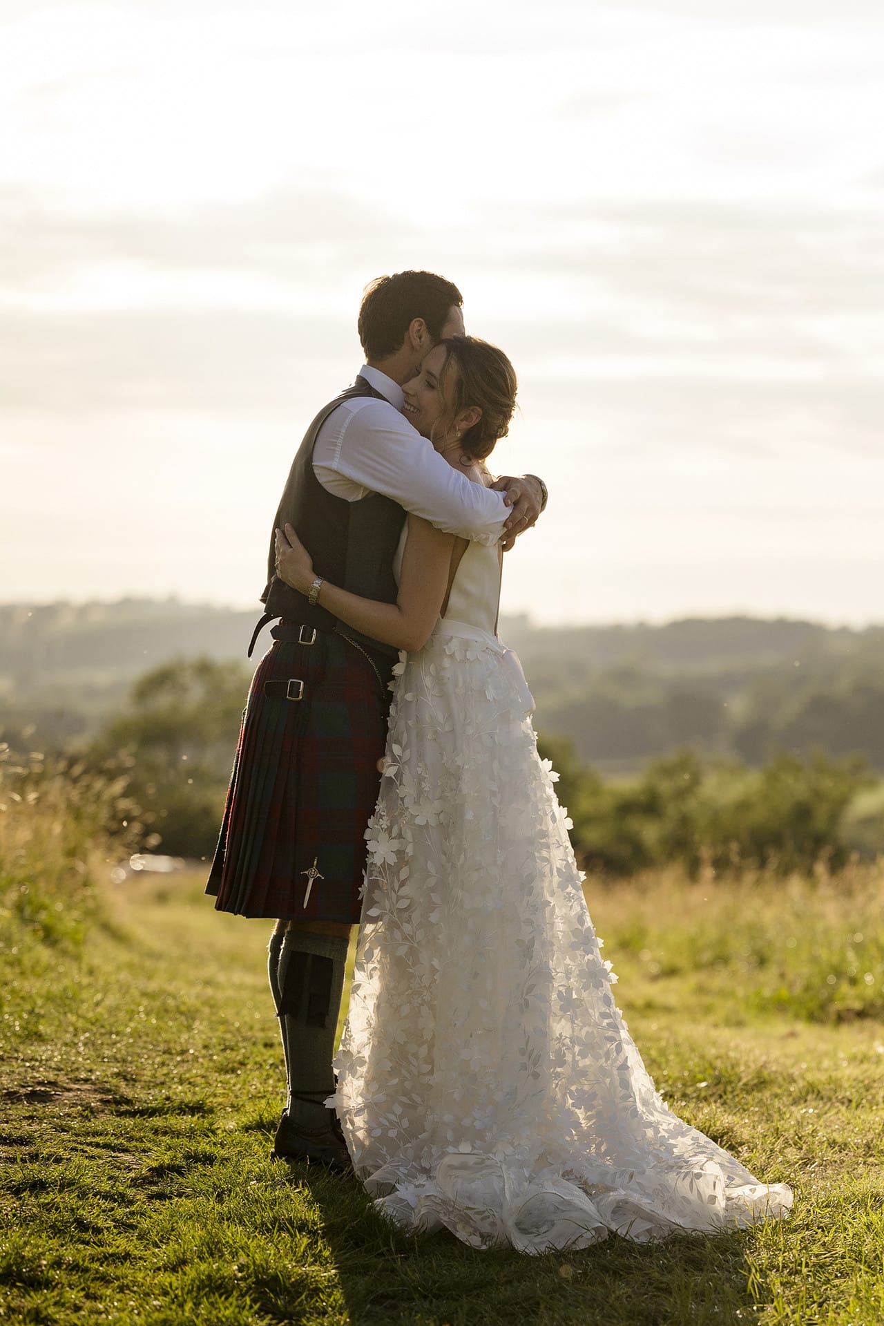 Bride and groom hugging in a field at golden hour