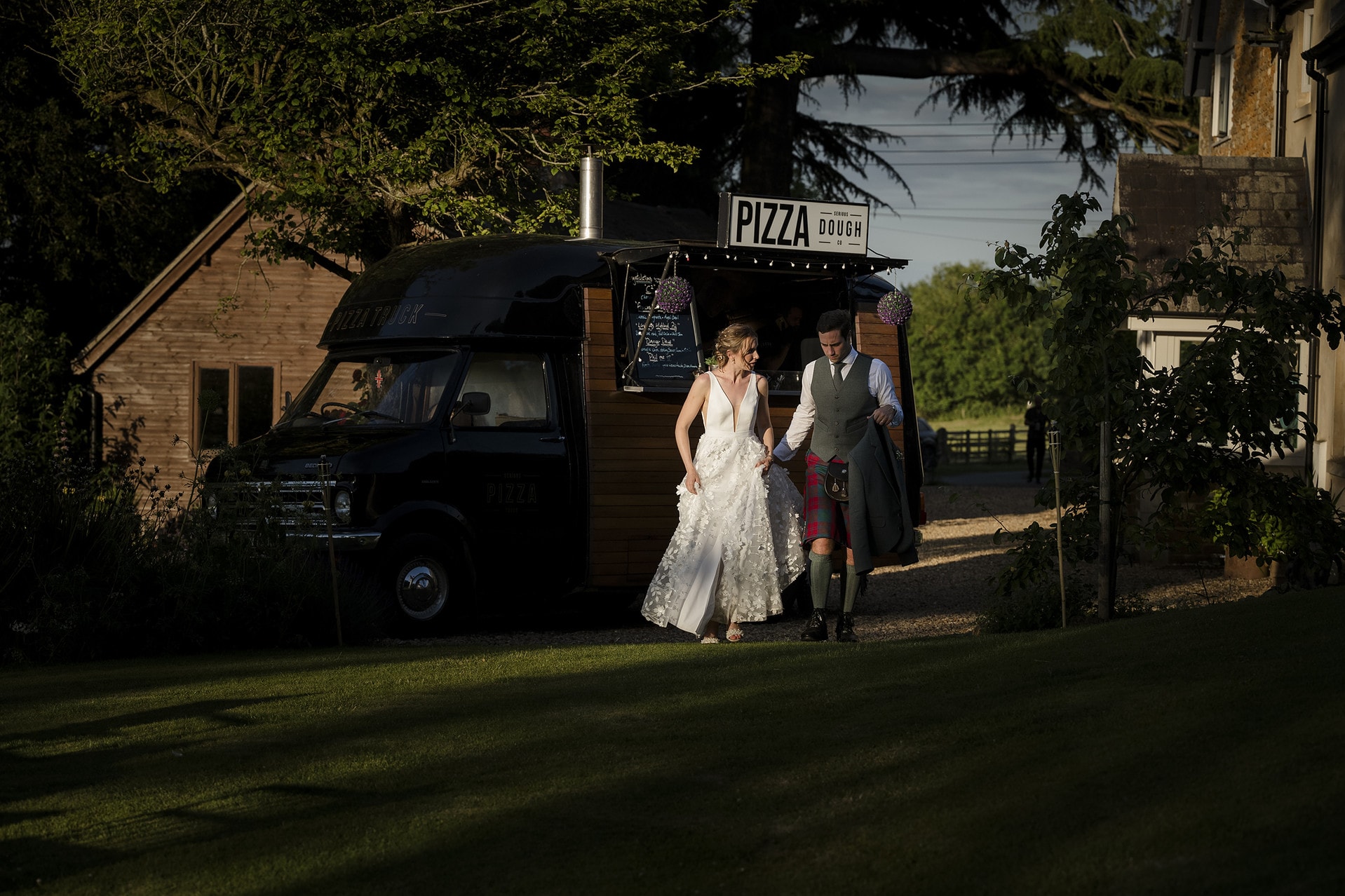 Bride and groom walking in front of a pizza van