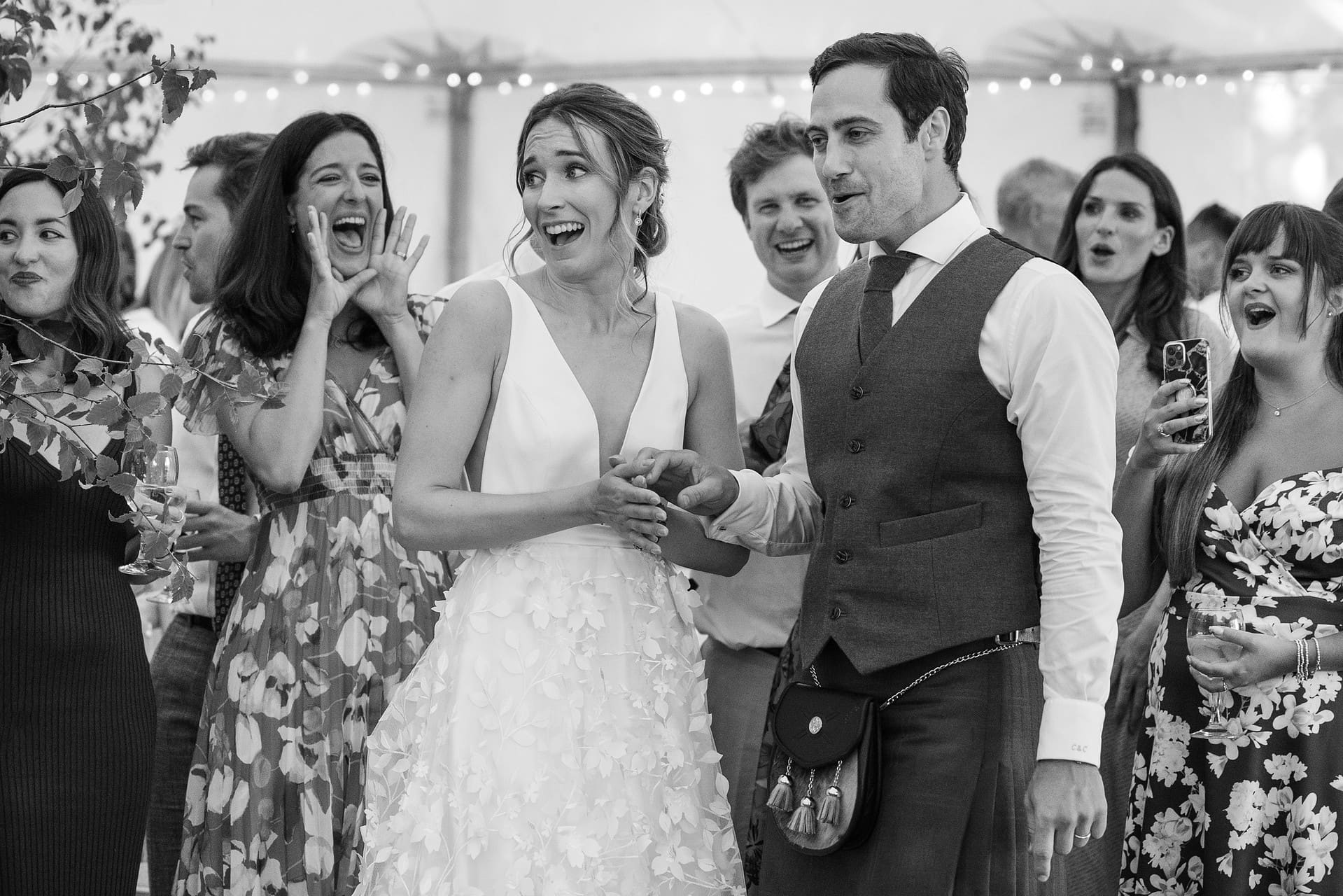 Bride and groom being cheered on by their wedding guests to start their first dance