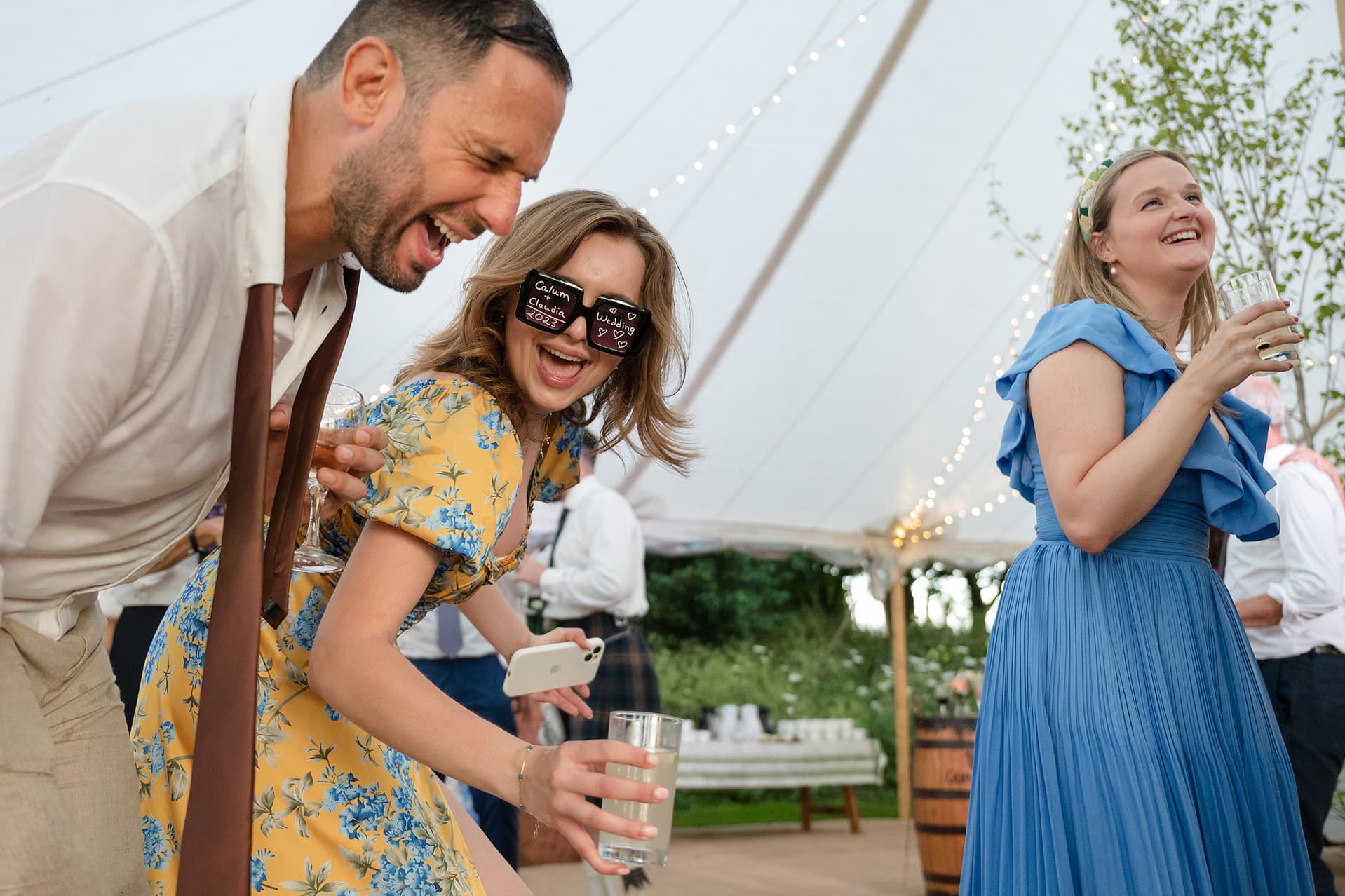 Three wedding guests laughing as they dance